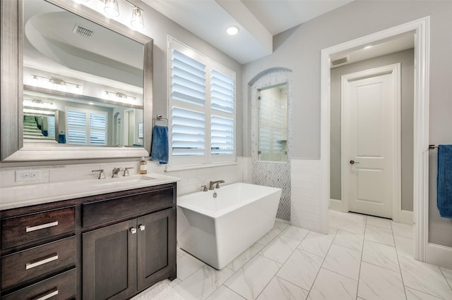 2021 Longmont Ln, Prosper, TX 75078 - full bathroom featuring a soaking tub, vanity, healthy amount of natural light, marble finish flooring, and wainscoting