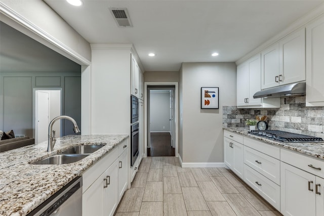 5004 Andover Dr, Plano, TX 75023 - kitchen with under cabinet range hood, appliances with stainless steel finishes, decorative backsplash, white cabinetry, and recessed lighting