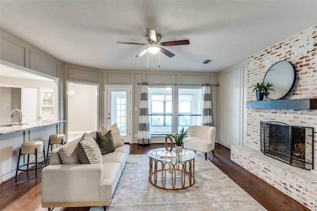 5004 Andover Dr, Plano, TX 75023 - living area with a decorative wall, ceiling fan, a fireplace, and wood finished floors