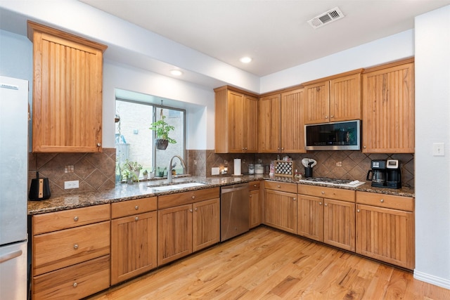 933 Oatlands Pl, Burleson, TX 76028 - kitchen with stainless steel appliances, a sink, light wood-style floors, dark stone counters, and recessed lighting