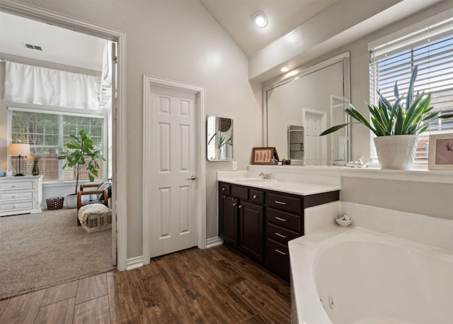 2541 Sir Tristram Ln, Lewisville, TX 75056 - bathroom with plenty of natural light, vanity, a whirlpool tub, lofted ceiling, and wood finished floors