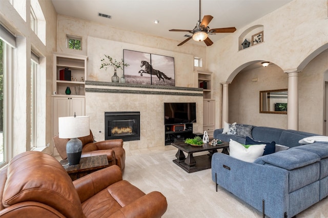 3873 Heritage Trl, Celina, TX 75009 - carpeted living room featuring arched walkways, built in features, decorative columns, ceiling fan, and a fireplace