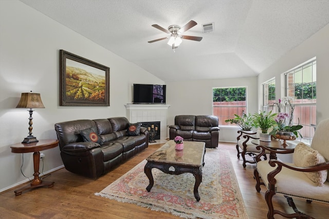 8217 Alderwood Pl, Plano, TX 75025 - living area with lofted ceiling, a ceiling fan, wood finished floors, a textured ceiling, and a fireplace