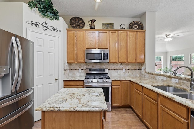 8217 Alderwood Pl, Plano, TX 75025 - kitchen featuring appliances with stainless steel finishes, a sink, a textured ceiling, backsplash, and light wood-type flooring