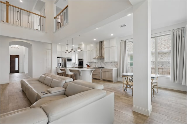 1001 Gentle Knoll Ln, Prosper, TX 75078 - living area featuring arched walkways, light wood-style flooring, a chandelier, and baseboards