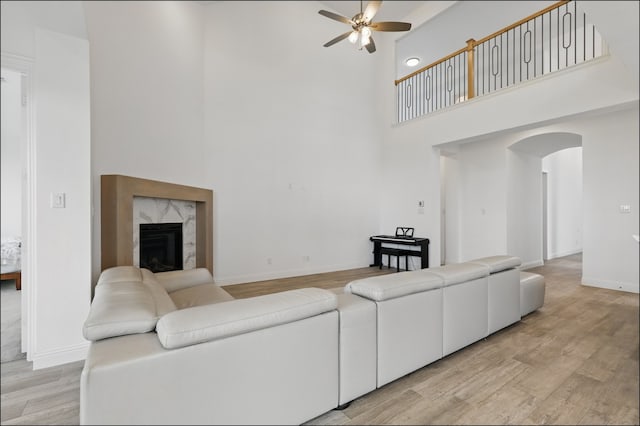1001 Gentle Knoll Ln, Prosper, TX 75078 - living room with a high ceiling, ceiling fan, arched walkways, light wood-style flooring, and a premium fireplace