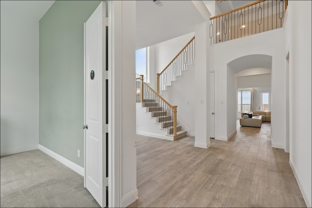 1001 Gentle Knoll Ln, Prosper, TX 75078 - stairs with arched walkways, a towering ceiling, wood finished floors, and baseboards