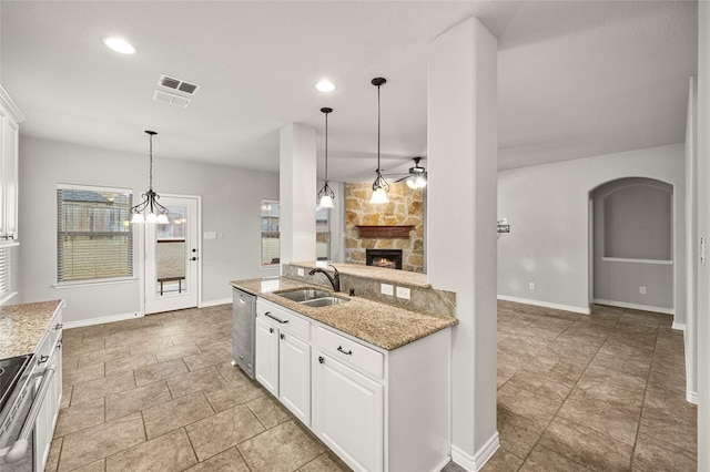 2408 Comal Ct, Royse City, TX 75189 - kitchen featuring a sink, baseboards, a stone fireplace, pendant lighting, and white cabinetry