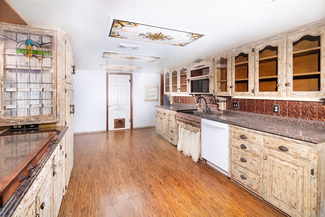 2992 County Road 100, Brady, TX 76825 - kitchen with dishwasher, a sink, backsplash, light wood-style floors, and glass insert cabinets