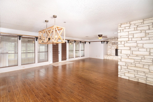 2992 County Road 100, Brady, TX 76825 - unfurnished living room with a textured ceiling, a chandelier, wood finished floors, and ceiling fan