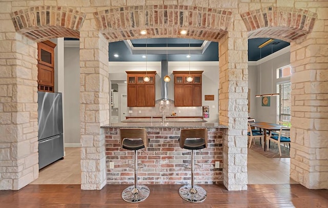 103 Saintsbury Cir, Waco, TX 76712 - kitchen featuring freestanding refrigerator, ornamental molding, ornate columns, arched walkways, and brown cabinetry