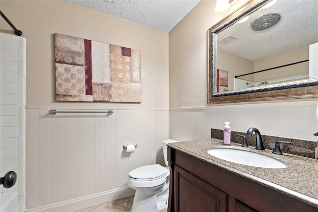 2507 16th St, Brownwood, TX 76801 - bathroom with a textured ceiling, vanity, a wainscoted wall, and toilet