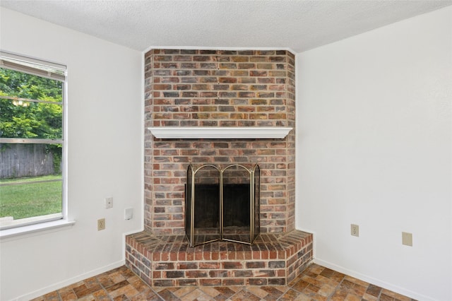 6003 Springwood Dr, Arlington, TX 76001 - unfurnished living room featuring a brick fireplace, baseboards, a textured ceiling, and stone finish floors