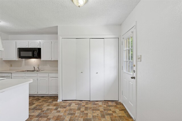 6003 Springwood Dr, Arlington, TX 76001 - kitchen with black microwave, a sink, white cabinets, light countertops, and a textured ceiling