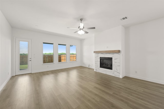 2397 Rams Horn Dr, Waxahachie, TX 75165 - unfurnished living room with wood finished floors, ceiling fan, baseboards, and a high end fireplace