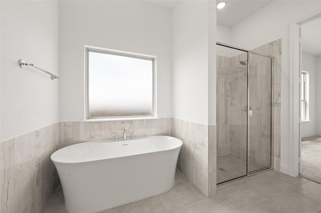 2397 Rams Horn Dr, Waxahachie, TX 75165 - full bathroom with a soaking tub, a stall shower, a wainscoted wall, and tile walls