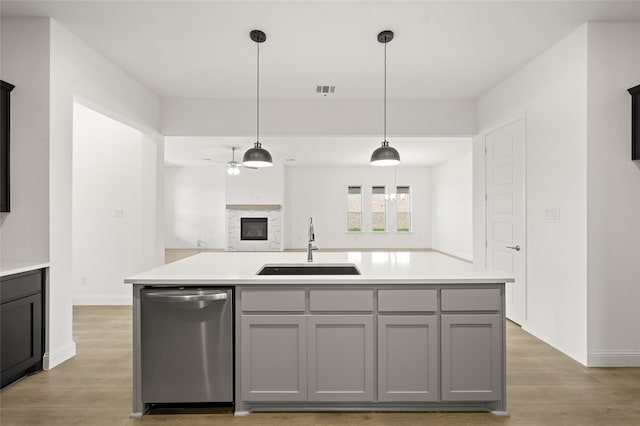 2397 Rams Horn Dr, Waxahachie, TX 75165 - kitchen with stainless steel dishwasher, a sink, gray cabinets, and light wood-type flooring