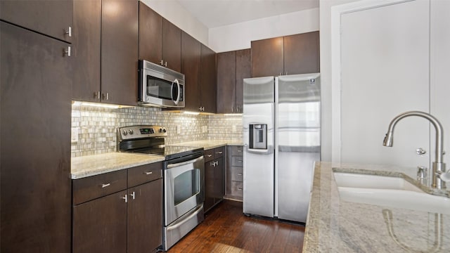2950 Mckinney Ave Unit 316, Dallas, TX 75204 - kitchen featuring appliances with stainless steel finishes, a sink, light stone counters, dark brown cabinetry, and backsplash