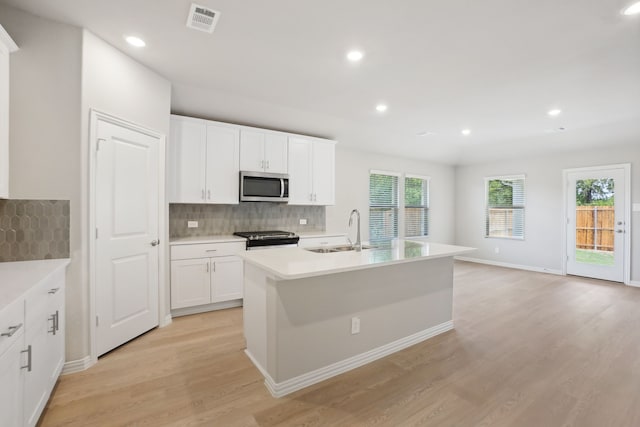 414 Stagg St, Mckinney, TX 75069 - kitchen featuring stainless steel microwave, a sink, stove, decorative backsplash, and light wood-type flooring