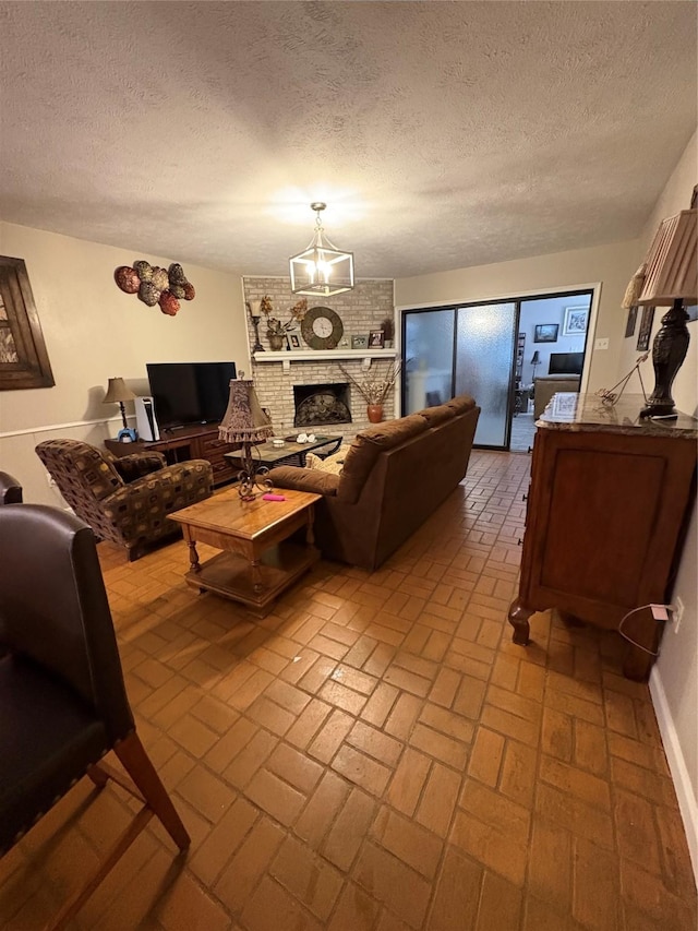 7750 Dentcrest Dr, Dallas, TX 75254 - living room featuring brick patterned flooring, a textured ceiling, a fireplace, a chandelier, and baseboards