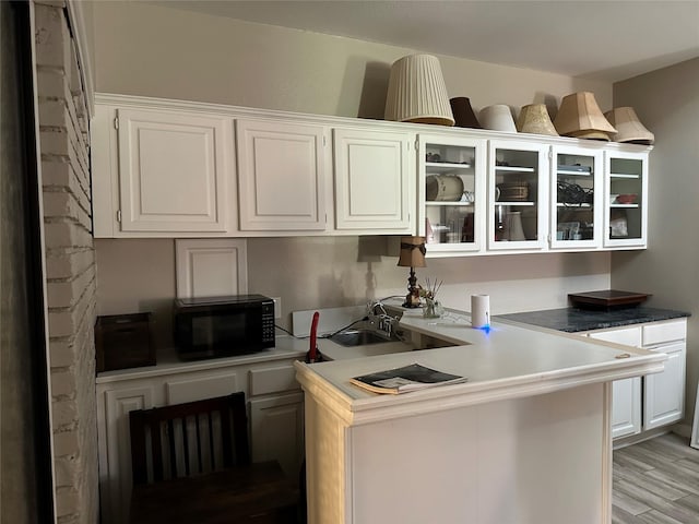 7750 Dentcrest Dr, Dallas, TX 75254 - kitchen featuring black microwave, white cabinetry, glass insert cabinets, light wood finished floors, and a sink