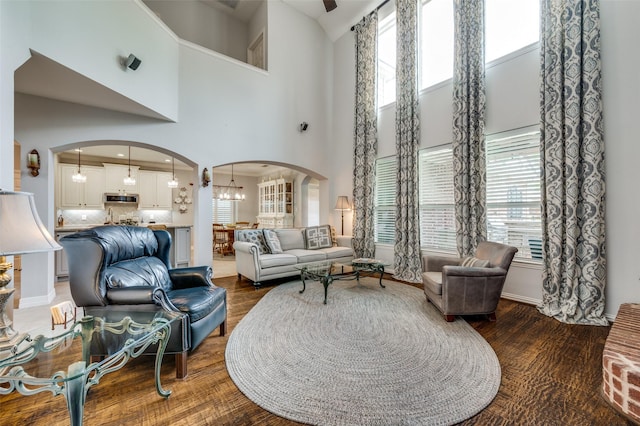 2362 Barret Dr, Frisco, TX 75033 - living room featuring arched walkways, a towering ceiling, healthy amount of natural light, wood finished floors, and a chandelier