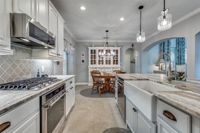 2362 Barret Dr, Frisco, TX 75033 - kitchen with appliances with stainless steel finishes, backsplash, a sink, arched walkways, and white cabinetry