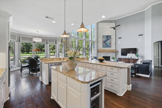 702 Malton Ln, Southlake, TX 76092 - kitchen with a kitchen island, stainless steel dishwasher, dark wood finished floors, a stone fireplace, and crown molding