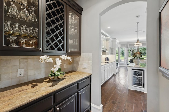 702 Malton Ln, Southlake, TX 76092 - bar area with arched walkways, dark wood-style floors, decorative backsplash, recessed lighting, and under cabinet range hood