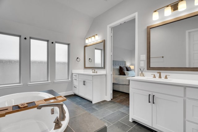 1210 Old Rocksprings Pass, Mansfield, TX 76063 - ensuite bathroom with two vanities, lofted ceiling, a tub, baseboards, and tile patterned flooring