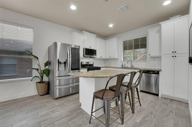 832 Lake Worth Trl, Little Elm, TX 75068 - kitchen with appliances with stainless steel finishes, a kitchen island, backsplash, white cabinets, and recessed lighting