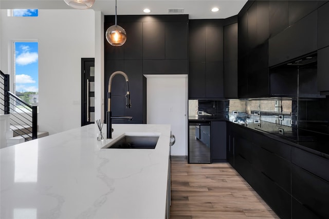 8356 Fairview Dr, Frisco, TX 75033 - kitchen featuring dark cabinets, a sink, modern cabinets, pendant lighting, and light wood-type flooring