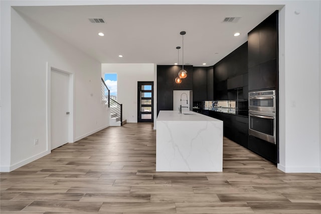 8356 Fairview Dr, Frisco, TX 75033 - kitchen featuring modern cabinets, dark cabinets, a sink, light wood finished floors, and recessed lighting