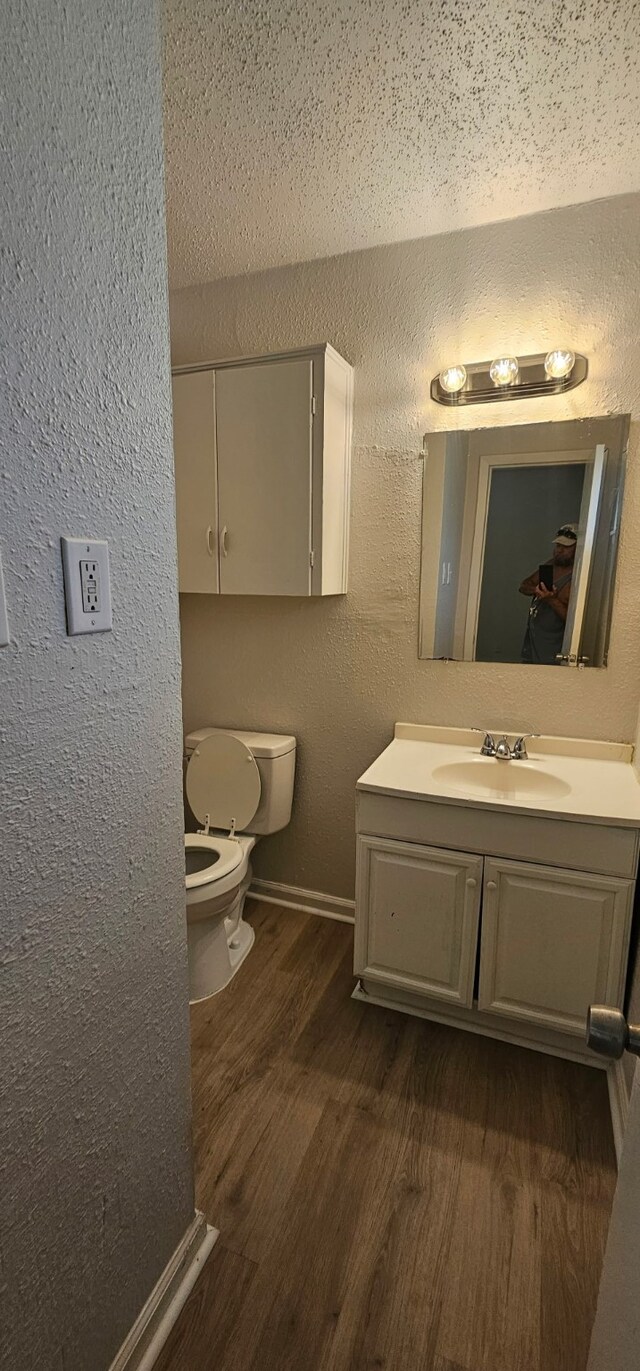 5170 Cardiff St, Dallas, TX 75241 - bathroom featuring wood finished floors, toilet, vanity, a textured wall, and baseboards