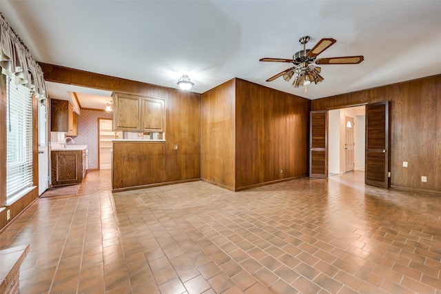 1122 Gloucester Ct N, Irving, TX 75062 - unfurnished living room featuring wood walls, a ceiling fan, brick patterned flooring, and a sink
