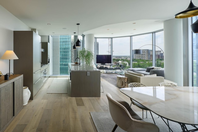 2900 Mckinnon St Unit 604, Dallas, TX 75201 - kitchen with a wall of windows, light wood finished floors, a sink, an island with sink, and decorative light fixtures