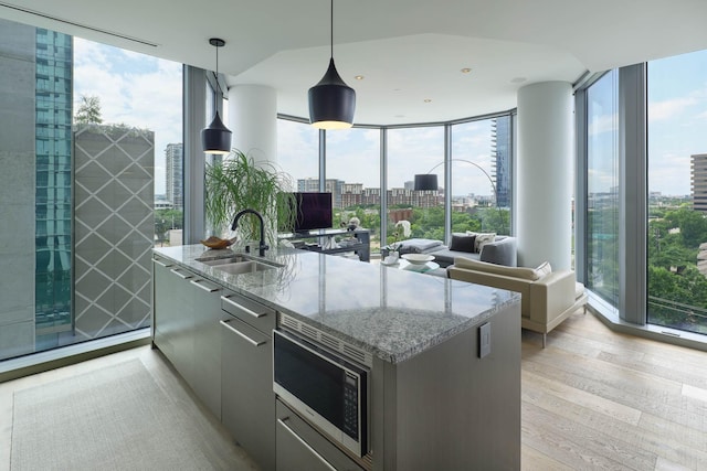 2900 Mckinnon St Unit 604, Dallas, TX 75201 - kitchen with stainless steel microwave, a sink, light wood-type flooring, plenty of natural light, and expansive windows