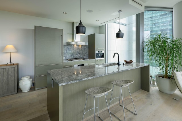 2900 Mckinnon St Unit 604, Dallas, TX 75201 - kitchen with a sink, modern cabinets, wall chimney range hood, light wood-style floors, and backsplash