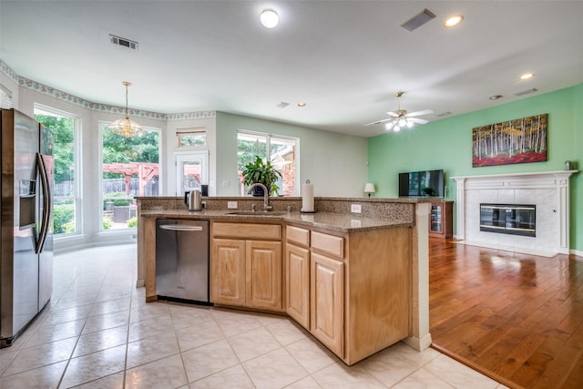 2925 Custer Dr, Corinth, TX 76210 - kitchen with stainless steel appliances, open floor plan, light stone countertops, a tile fireplace, and a ceiling fan