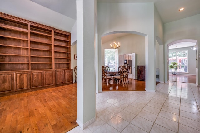 2925 Custer Dr, Corinth, TX 76210 - hall with arched walkways, light wood-style flooring, a towering ceiling, a chandelier, and baseboards