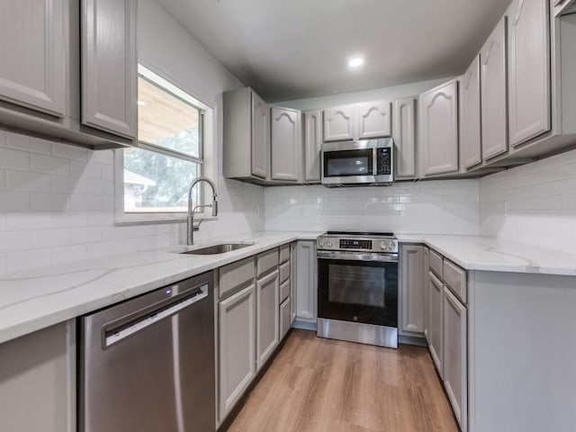 2032 Meadfoot Rd, Carrollton, TX 75007 - kitchen featuring appliances with stainless steel finishes, a sink, gray cabinets, light wood-style flooring, and light stone counters