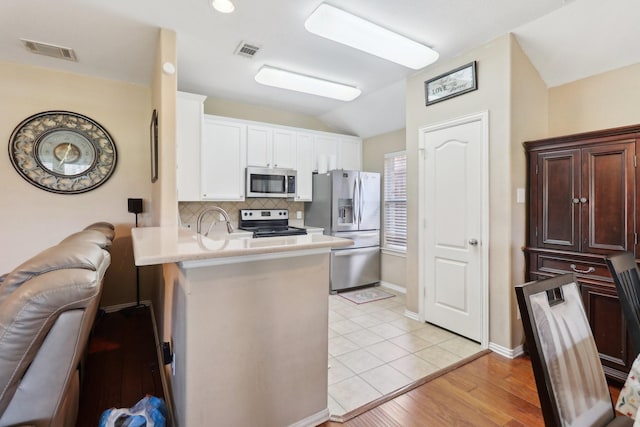 14709 Crystal Lake Dr, Little Elm, TX 75068 - kitchen with stainless steel appliances, a peninsula, tasteful backsplash, vaulted ceiling, and light countertops