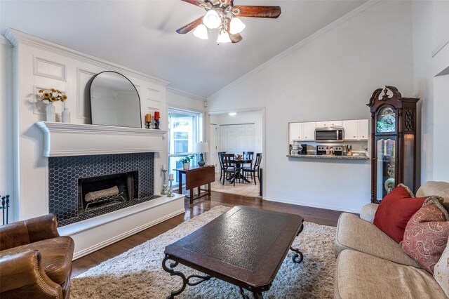 8070 Rock Brook St, Frisco, TX 75034 - living room featuring a ceiling fan, a fireplace with raised hearth, dark wood-style floors, high vaulted ceiling, and ornamental molding