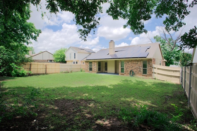 4136 Periwinkle Dr, Fort Worth, TX 76137 - back of house with roof mounted solar panels, a chimney, a patio, and brick siding