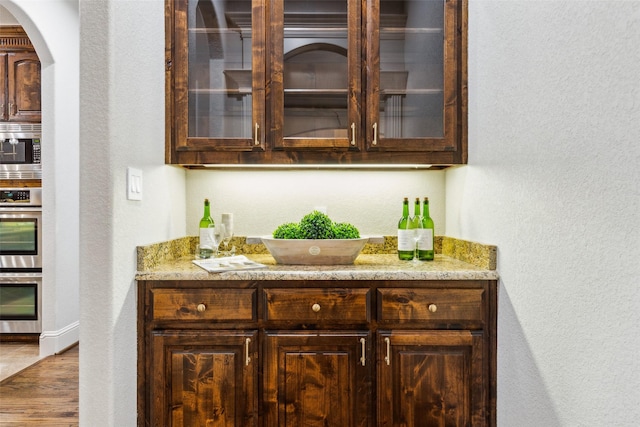 1516 Hawthorne Ln, Keller, TX 76262 - indoor dry bar with stainless steel appliances, a textured wall, wood finished floors, arched walkways, and baseboards