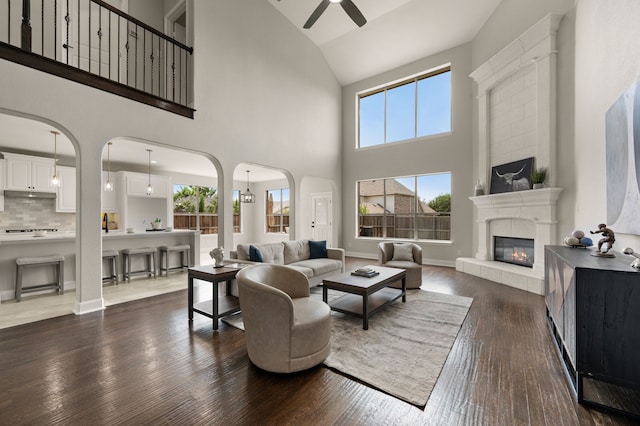 850 White River Dr, Prosper, TX 75078 - living area featuring a ceiling fan, high vaulted ceiling, arched walkways, dark wood-style floors, and a fireplace