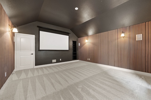 850 White River Dr, Prosper, TX 75078 - carpeted home theater room with vaulted ceiling, wood walls, and a textured ceiling