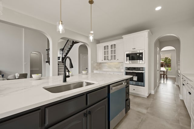 850 White River Dr, Prosper, TX 75078 - kitchen with stainless steel appliances, a sink, white cabinetry, decorative backsplash, and arched walkways
