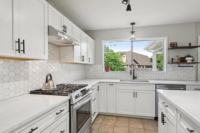 6128 Redear Dr, Fort Worth, TX 76179 - kitchen with a sink, stainless steel gas range, under cabinet range hood, white cabinetry, and light tile patterned floors