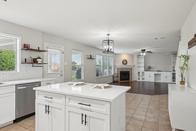 6128 Redear Dr, Fort Worth, TX 76179 - kitchen with dishwasher, light tile patterned floors, a ceiling fan, white cabinetry, and a tiled fireplace